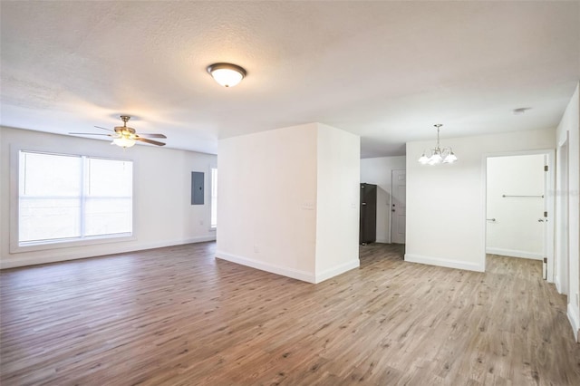 unfurnished living room featuring ceiling fan with notable chandelier, a textured ceiling, electric panel, and light hardwood / wood-style floors