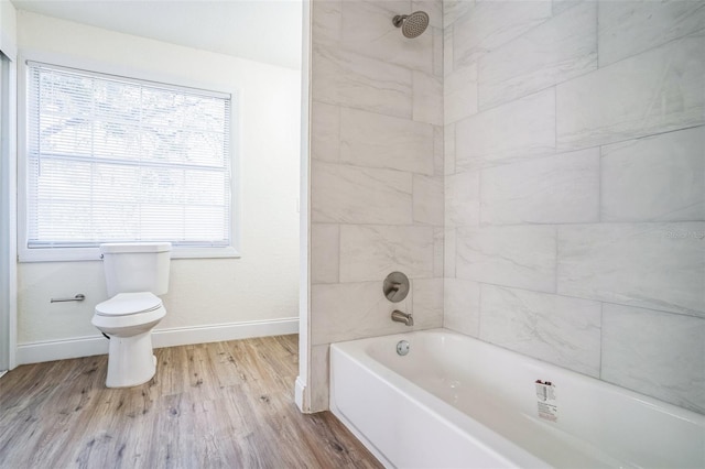 bathroom with wood-type flooring, toilet, and tiled shower / bath