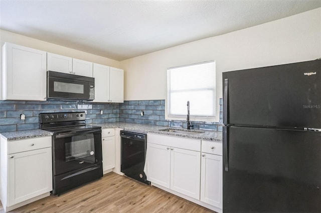 kitchen with backsplash, black appliances, white cabinets, sink, and light hardwood / wood-style floors