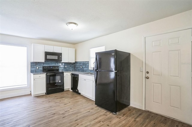 kitchen with decorative backsplash, white cabinetry, and black appliances