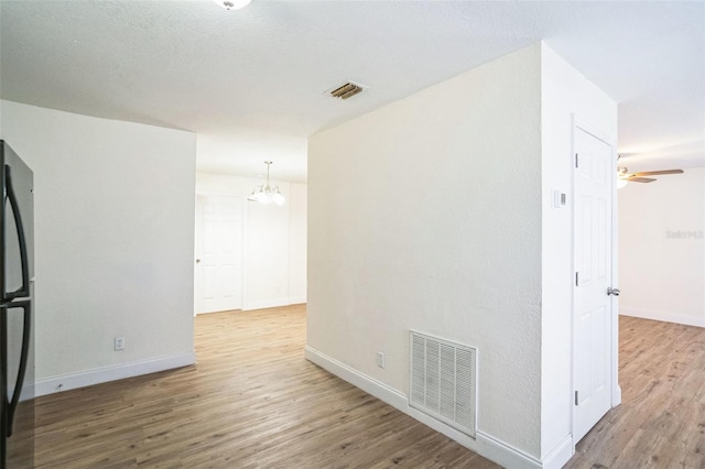 spare room featuring hardwood / wood-style floors and ceiling fan with notable chandelier