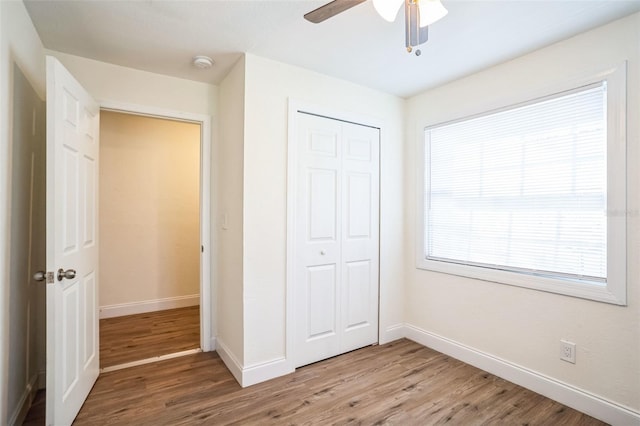 unfurnished bedroom with ceiling fan, a closet, and hardwood / wood-style floors