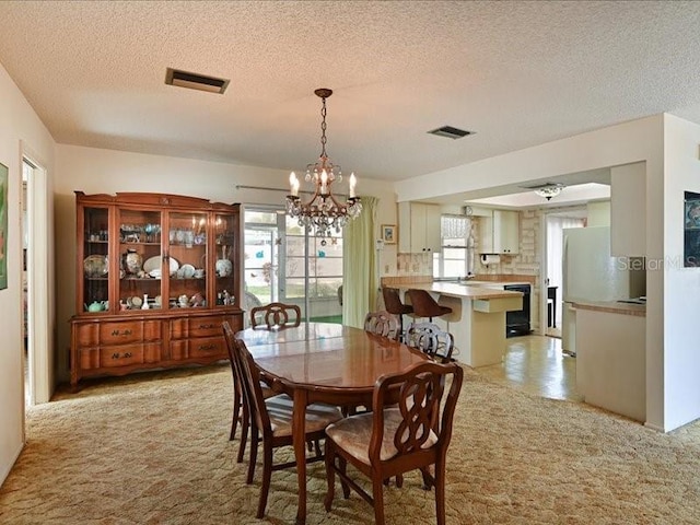 carpeted dining space with a textured ceiling and an inviting chandelier