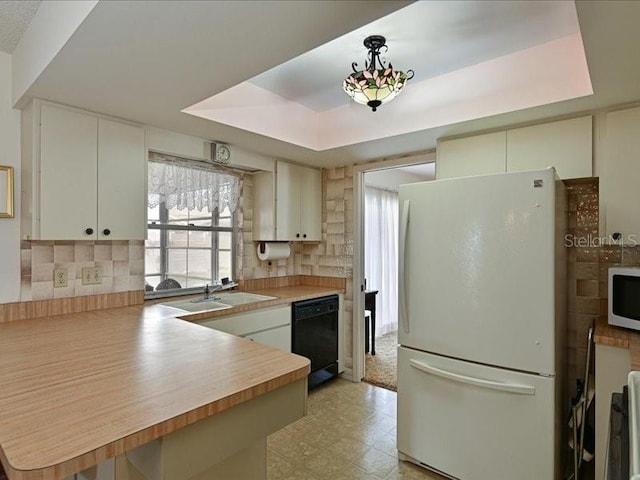 kitchen featuring a raised ceiling, kitchen peninsula, sink, and white appliances