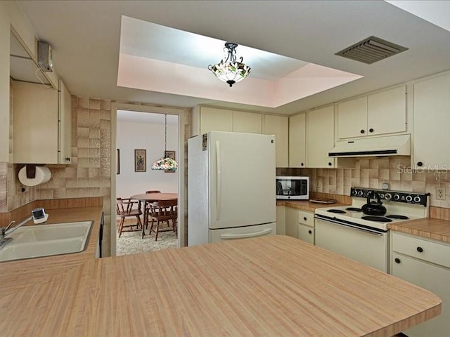 kitchen featuring decorative backsplash, sink, white appliances, and cream cabinetry