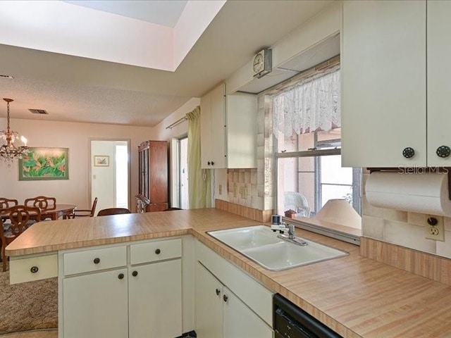 kitchen featuring black dishwasher, kitchen peninsula, sink, and a notable chandelier