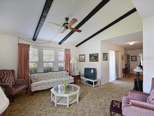 living room featuring carpet flooring, a textured ceiling, lofted ceiling with beams, and ceiling fan