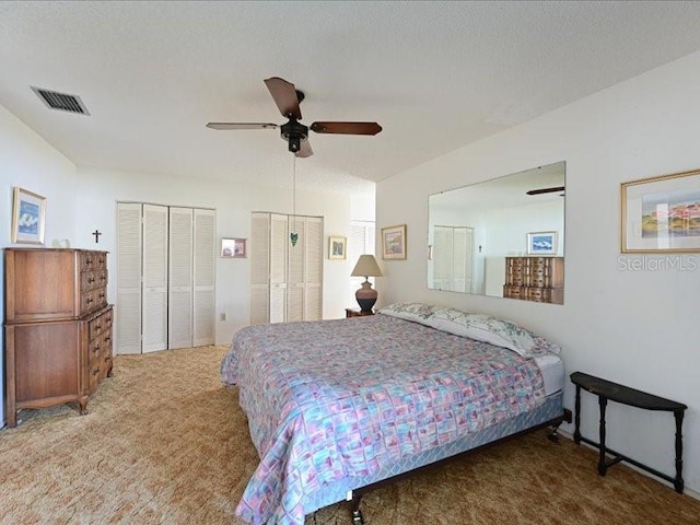 bedroom featuring carpet, a textured ceiling, two closets, and ceiling fan