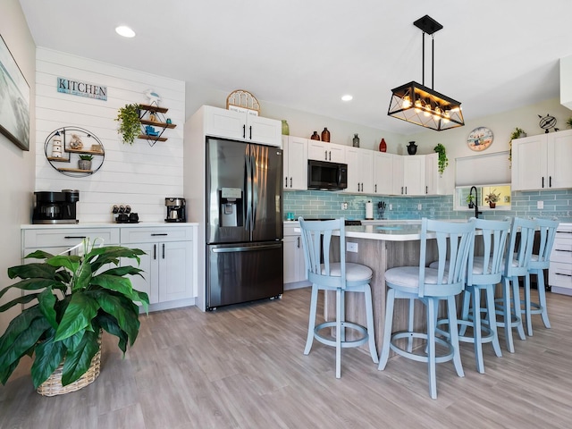 kitchen with white cabinetry, stainless steel fridge with ice dispenser, light hardwood / wood-style flooring, and hanging light fixtures