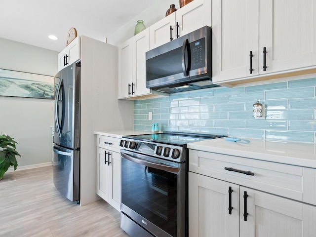 kitchen with white cabinets, light wood-type flooring, stainless steel appliances, and tasteful backsplash