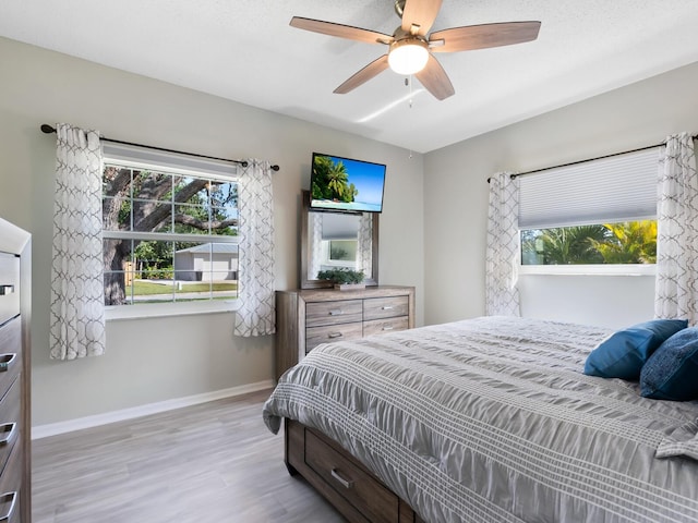 bedroom featuring multiple windows, light wood-type flooring, and ceiling fan