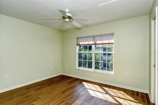 spare room with a textured ceiling, ceiling fan, and dark wood-type flooring