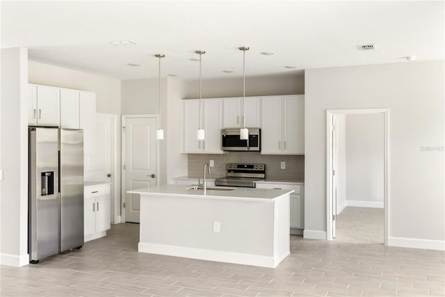 kitchen featuring appliances with stainless steel finishes, sink, decorative light fixtures, white cabinetry, and an island with sink