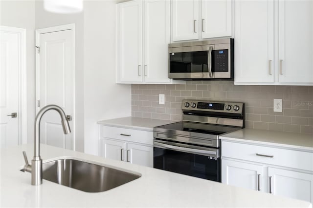 kitchen featuring white cabinets, sink, stainless steel appliances, and tasteful backsplash