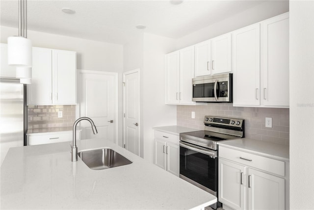 kitchen featuring tasteful backsplash, hanging light fixtures, white cabinets, and stainless steel appliances