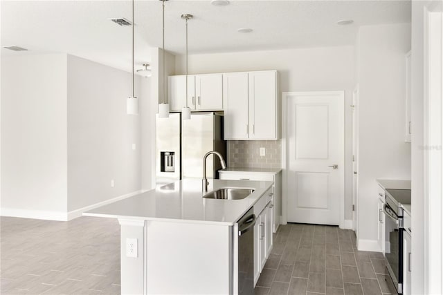 kitchen featuring white cabinetry, sink, an island with sink, decorative light fixtures, and appliances with stainless steel finishes