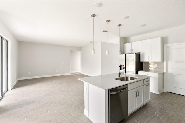 kitchen featuring backsplash, hanging light fixtures, an island with sink, appliances with stainless steel finishes, and white cabinetry