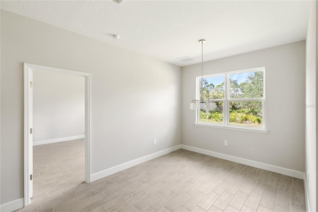 spare room featuring a textured ceiling and light wood-type flooring