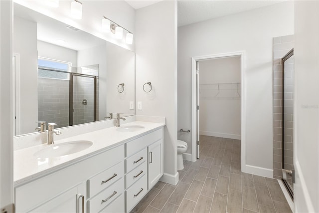 bathroom with vanity, toilet, and a shower with door