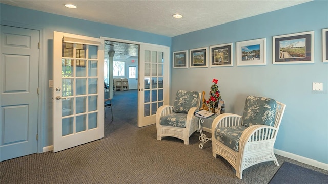 sitting room with a textured ceiling, dark carpet, and french doors