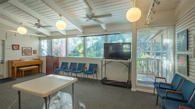 interior space with ceiling fan, dark carpet, and beamed ceiling