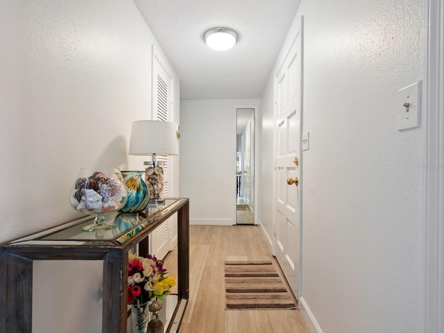 corridor featuring light wood-type flooring and a textured ceiling