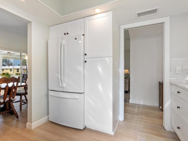 kitchen with white cabinetry, ceiling fan, light hardwood / wood-style flooring, white fridge, and decorative backsplash