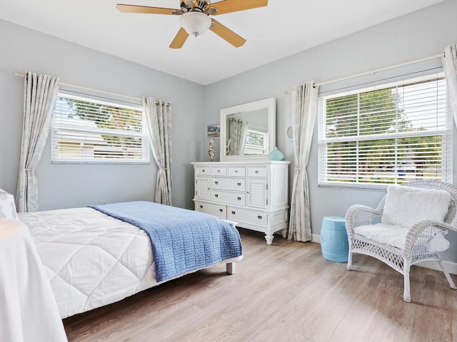 bedroom with multiple windows, ceiling fan, and light hardwood / wood-style floors