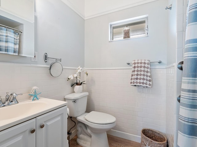 bathroom featuring crown molding, wood-type flooring, toilet, vanity, and tile walls