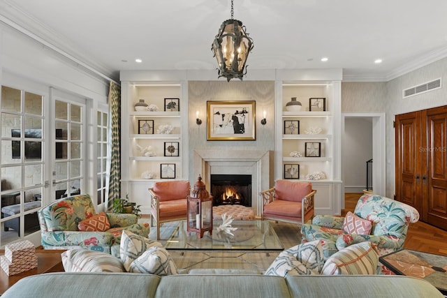 living room featuring wood-type flooring, an inviting chandelier, ornamental molding, and built in shelves