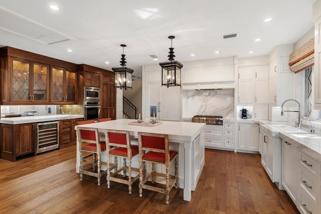 kitchen featuring wine cooler, stainless steel appliances, a center island, hardwood / wood-style flooring, and tasteful backsplash