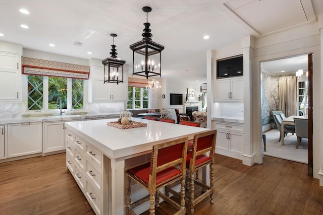 kitchen featuring sink, white cabinets, a center island, decorative backsplash, and dark wood-type flooring