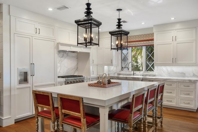 kitchen featuring pendant lighting, dark wood-type flooring, a kitchen island, decorative backsplash, and an inviting chandelier