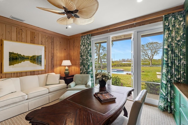 carpeted living room featuring wood walls and ceiling fan