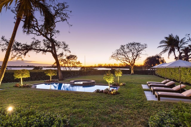 yard at dusk featuring an in ground hot tub