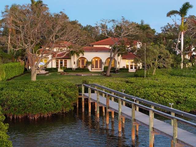 view of dock with a lawn and a water view