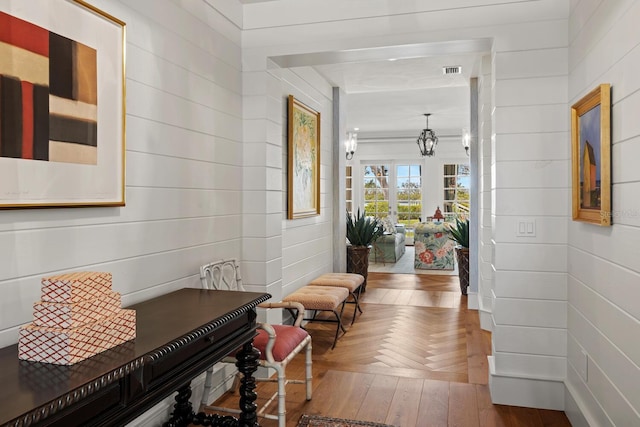corridor featuring parquet floors, a notable chandelier, and visible vents