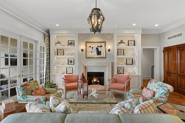 living room with visible vents, crown molding, a lit fireplace, and built in shelves