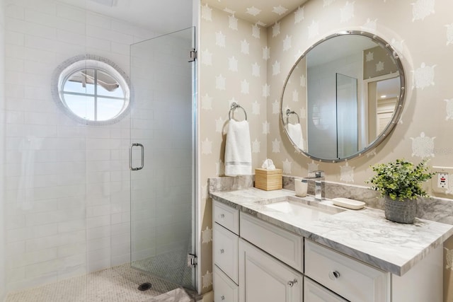 full bathroom with wallpapered walls, vanity, and a stall shower