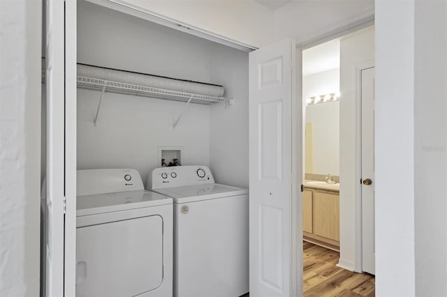 clothes washing area featuring light hardwood / wood-style floors, independent washer and dryer, and sink