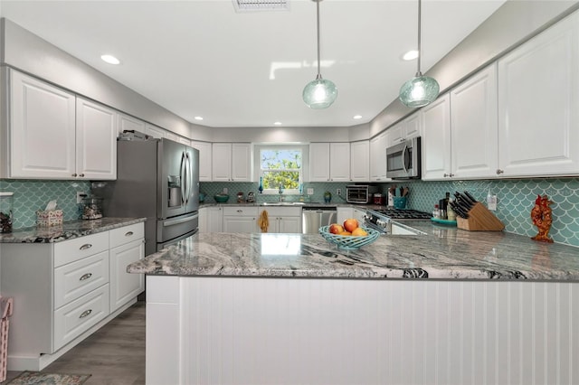 kitchen featuring white cabinetry, light stone counters, decorative light fixtures, kitchen peninsula, and stainless steel appliances