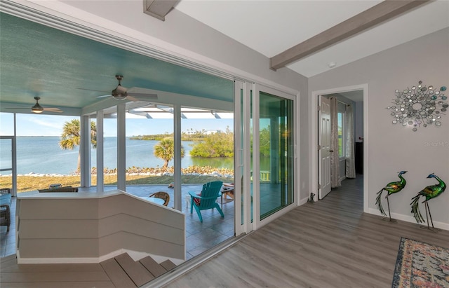 sunroom with a water view, a healthy amount of sunlight, and vaulted ceiling with beams