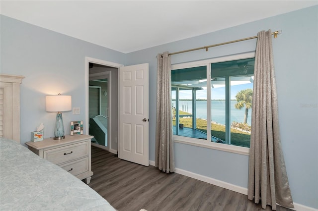 bedroom with dark wood-type flooring and a water view