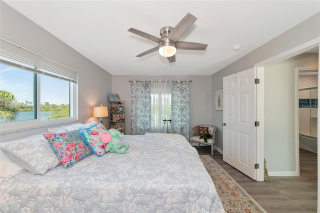 bedroom featuring a water view, hardwood / wood-style floors, and ceiling fan