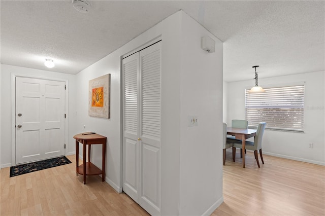 entryway with light wood-type flooring and a textured ceiling