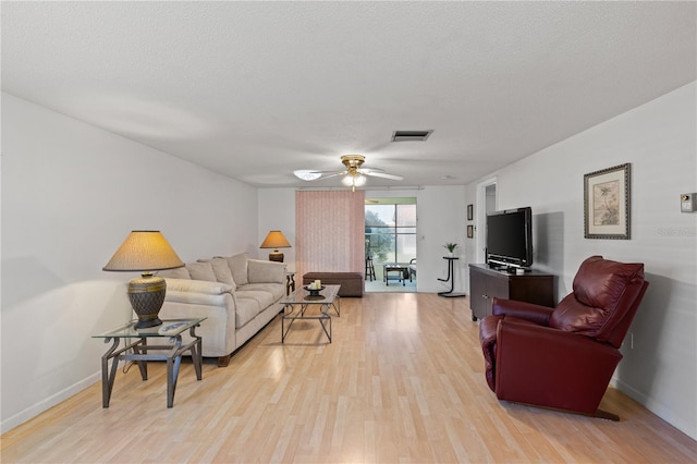 living room featuring a textured ceiling, light hardwood / wood-style flooring, and ceiling fan