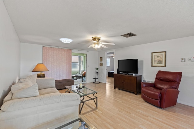 living room featuring a textured ceiling, light hardwood / wood-style floors, and ceiling fan