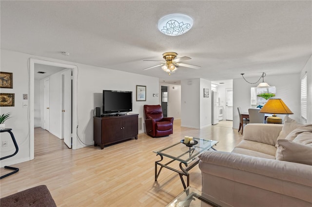 living room featuring a textured ceiling, light wood-type flooring, and ceiling fan