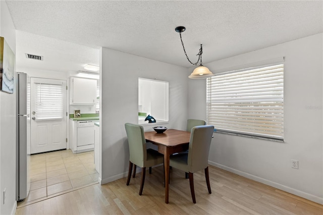 dining space with a textured ceiling and light hardwood / wood-style flooring