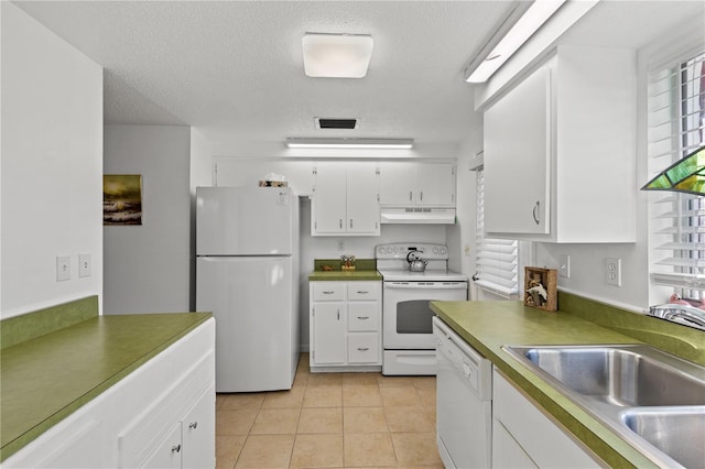 kitchen featuring white appliances, white cabinets, sink, light tile patterned floors, and a textured ceiling